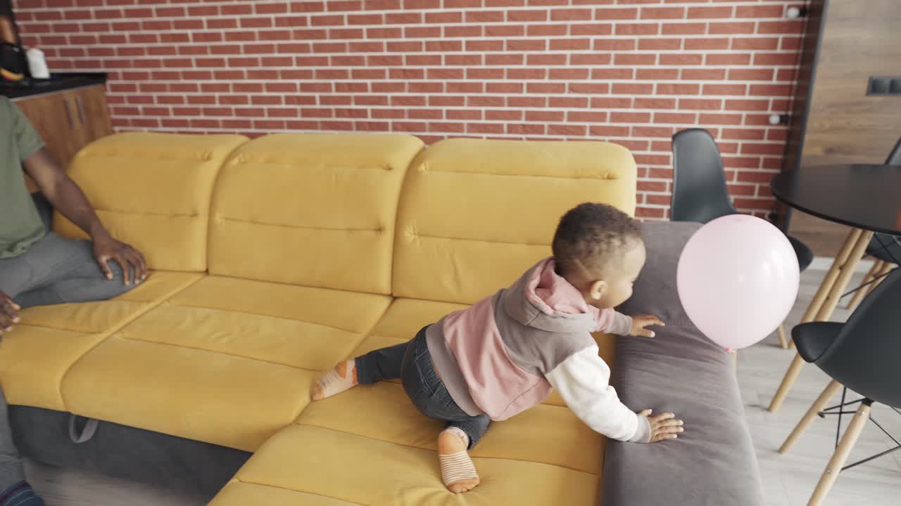 padre afroamericano jugando con un niño pequeño en la sala de estar