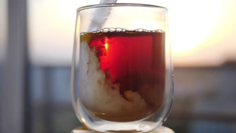 pouring milk in glass cup of tea