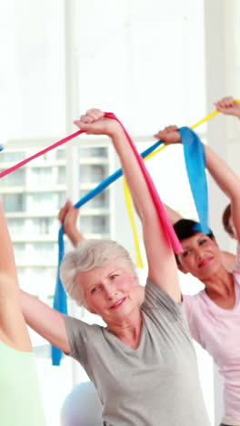 mujeres estirando bandas de resistencia en una clase de fitness