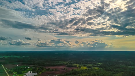 stunning aerial hyperlapse flies over vast latvian landscape with green forests, lakes, and agricultural fields as dramatic clouds move across the sky