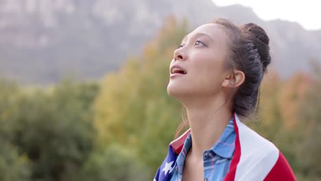 Portrait-of-biracial-woman-holding-flag-of-usa-in-garden,-slow-motion