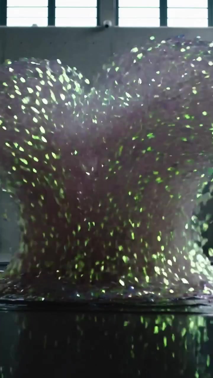 Vertical video: Rising glitter burst surging from tray on dark table under windows forming puddle