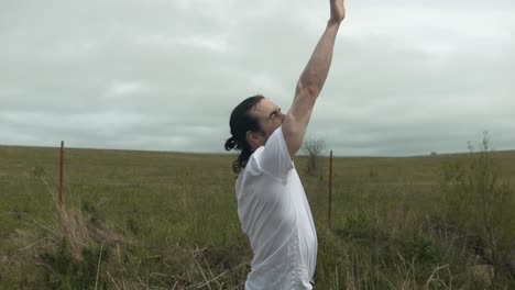 man in white shirt raising his hand reaching for the sky