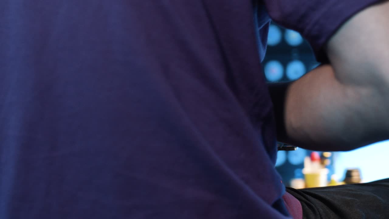 티셔츠를 입은 남자가 어두운 방에 앉아 손가락으로 휴대용 키보드를 청소하고 있습니다.