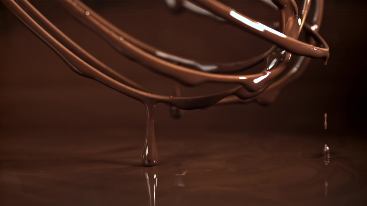 Cioccolato fuso che cola da una frusta al rallentatore