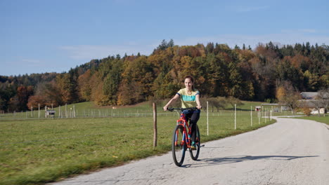 girl riding a bike along the countryside road on a sunny autumn day, handheld