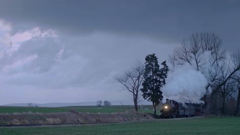 steam train chugging through the countryside under a dramatic sky