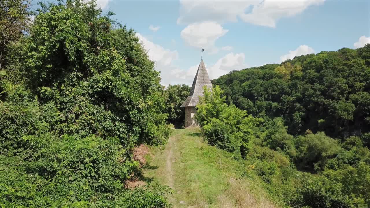 Aerial forward towards Kushnirska Tower surrounded with greenery,sunny day with beautiful white clouds at Kamianets Podilski,Ukraine.