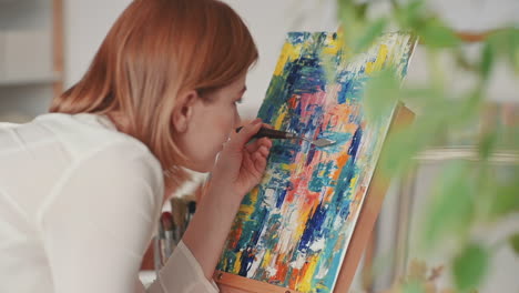 a red haired girl paints a very colorful impressionist painting