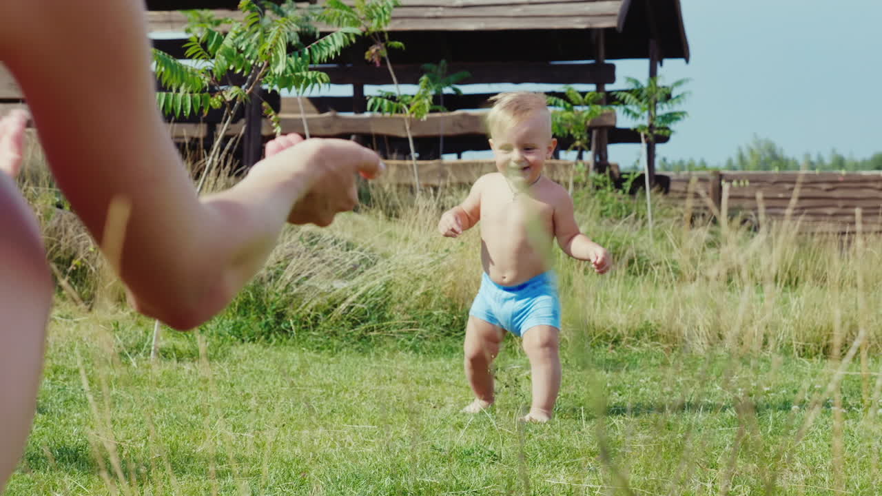 아기의 첫 발걸음 1살 소년 불확실하게 엄마에게 가는 슬로우 모션 비디오