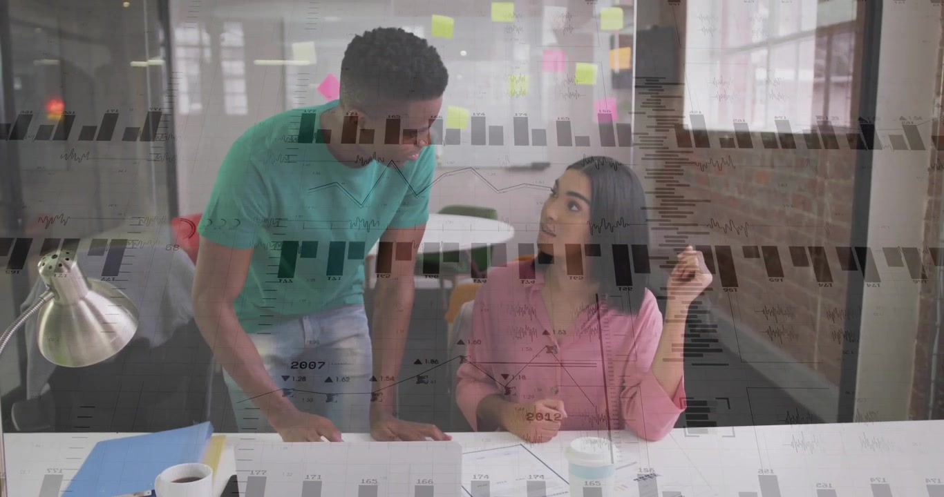 Colega masculino señalando gráficos, guiando a colega femenina que anota un informe en la oficina