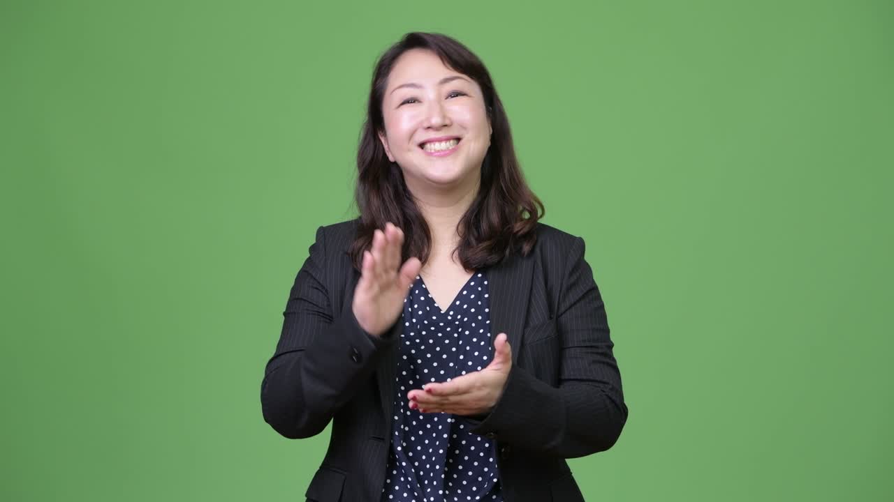 성숙하고 행복한 아시아 사업가 여성이 박수를 치고 있습니다.