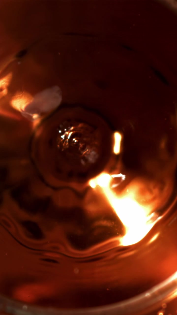 Top View of a Liquid Drop Splashing in Dark Amber Fluid