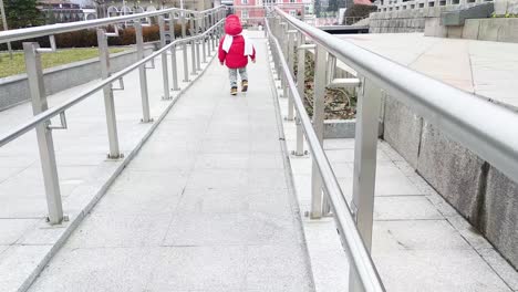 niño corriendo con una chaqueta roja y una bufanda blanca