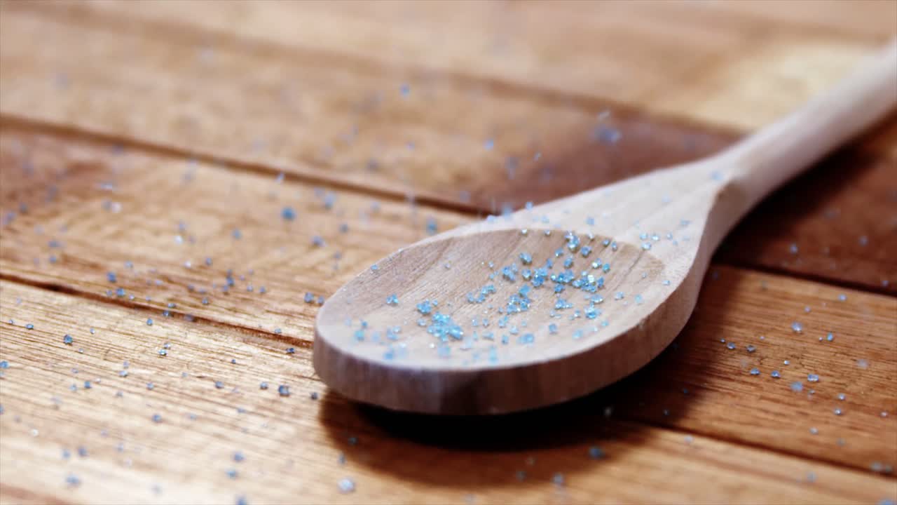 Crystals of blue frit glass falling wooden spoon