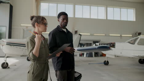 female aircraft inspector talking to male mechanic in airplane hangar