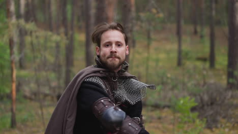 man in armor wields sword in forest, fencing