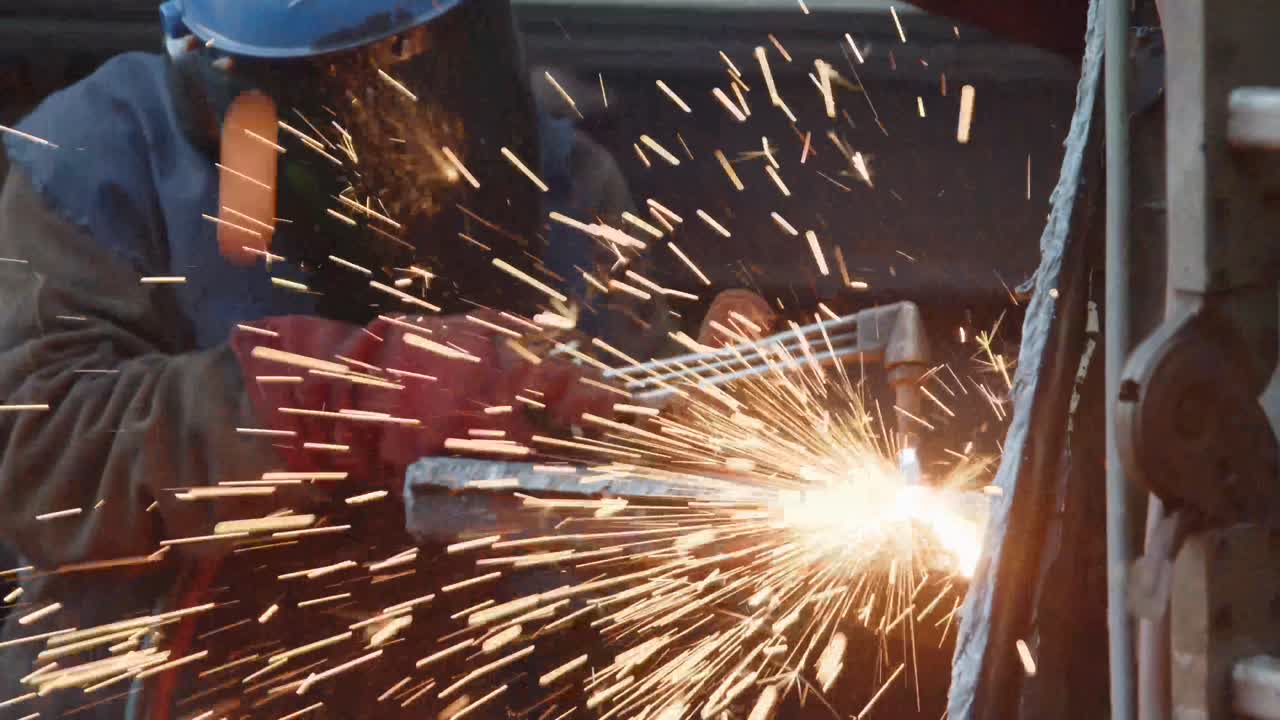 Man with welder cutting trough a piece of metal