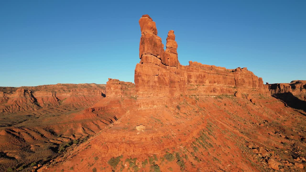 Un drone sorvola le formazioni di arenaria di Rudolph e Babbo Natale nella Valley of the Gods, Utah, USA. La luce bassa del sole illumina crepe e curve, con Castle Butte e Stagecoach Rock visibili nelle vicinanze sotto un cielo terso.