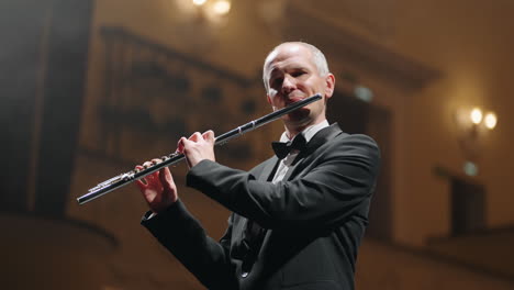 flutist is playing flute portrait of musician in concert hall of philharmonic brass band or symphonic orchestra