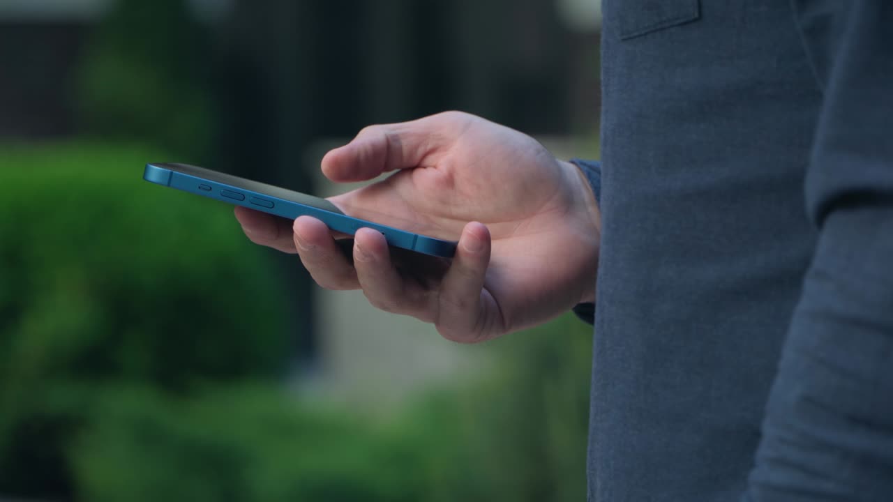 joven usa teléfono inteligente en la calle en el centro de la ciudad. primer plano de teléfono inteligente en las manos. 4k