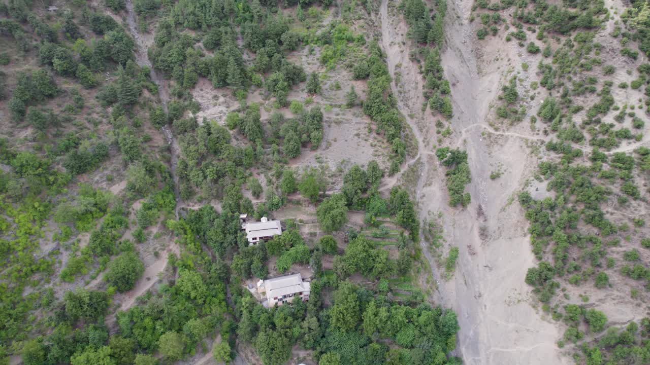casa de montaña rodeada de densa vegetación, adyacente a un área de deslizamiento de tierra en cachemira, india