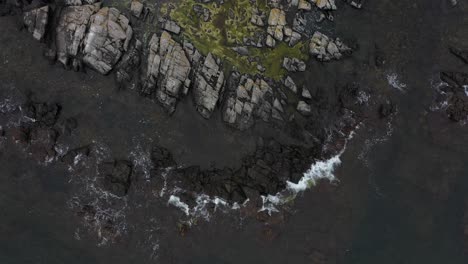 Birdseye-view-of-waves-hitting-the-shoreline-in-Bornholm,-Danish-island