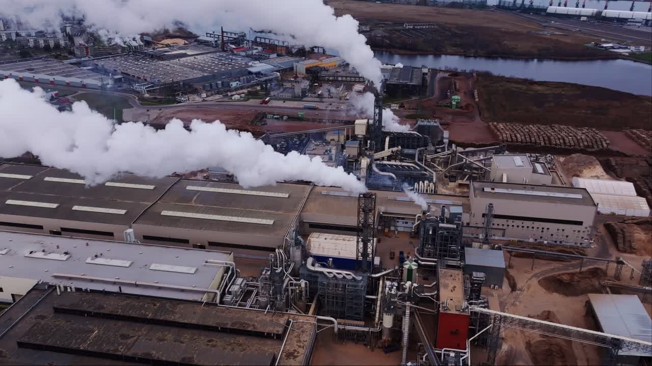 Heavy emissions from chimneys rising over snowy ground in Baltic industrial hub