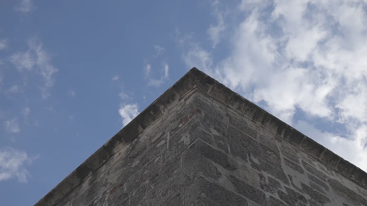 Inquadratura dal basso di un angolo di edificio contro un cielo nuvoloso.