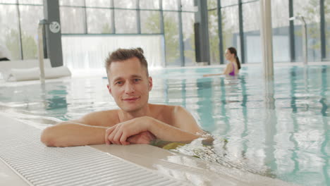 hombre relajándose en la piscina cubierta con su familia