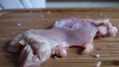 removing leftover skin of raw chicken meat using knife - high angle, close up