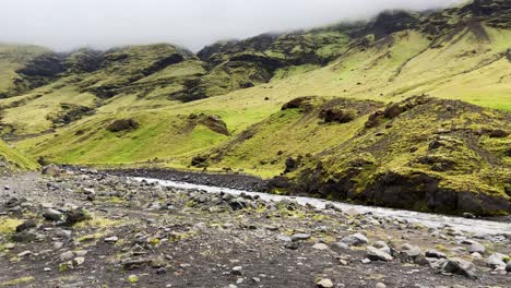 seljavallalaug river flowing under moss covered misty icelandic mountain summit