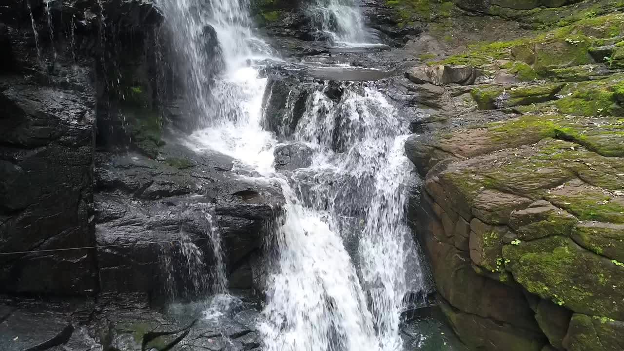 Drone approaches a stunning waterfall nestled within the jungle