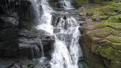 drone approaches a stunning waterfall nestled within the jungle