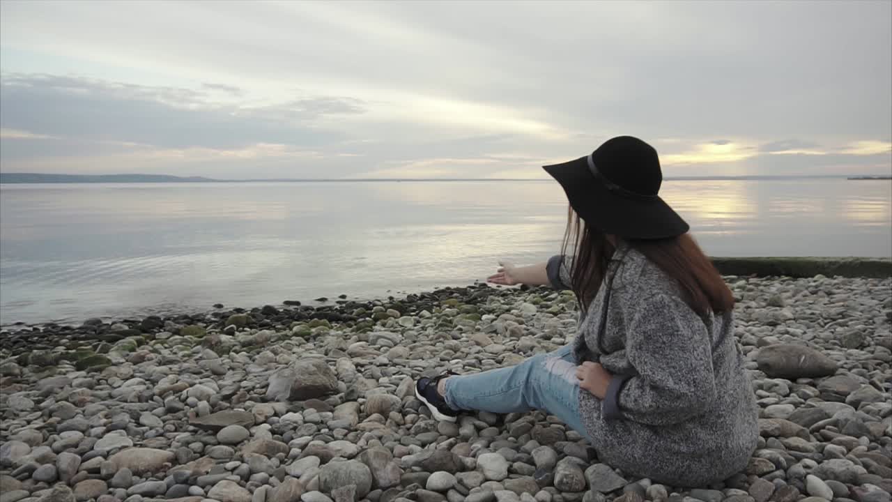 Woman sitting on a beach at sunset