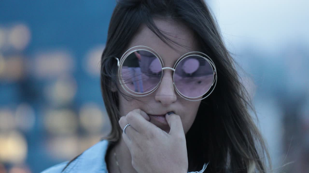 chica posando con gafas de sol grandes y redondas por la noche