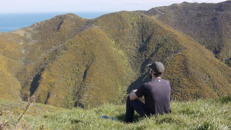 a day hiker standing up and putting on a backpack before leaving with a beautiful view