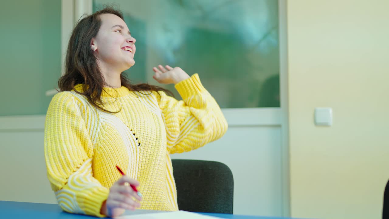 Teen girl studying at school. Beautiful smiling girl in yellow sweater writing a composition on a paper in classroom. Learning process.