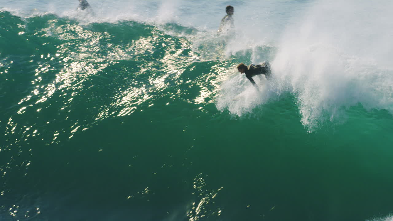 Surfer paddles and kicks to drop in on huge wave attempting a late drop in and going over the falls in slow motion