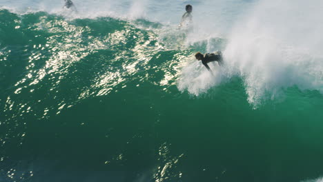 surfer paddles and kicks to drop in on huge wave attempting a late drop in and going over the falls in slow motion