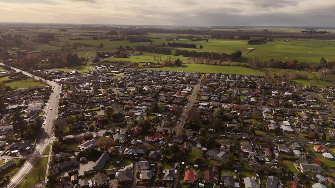 A beautiful 4K 60fps drone shot of residential houses in the town of Geraldine at sunset. The warm, golden light of the evening illuminates the rooftops and streets below