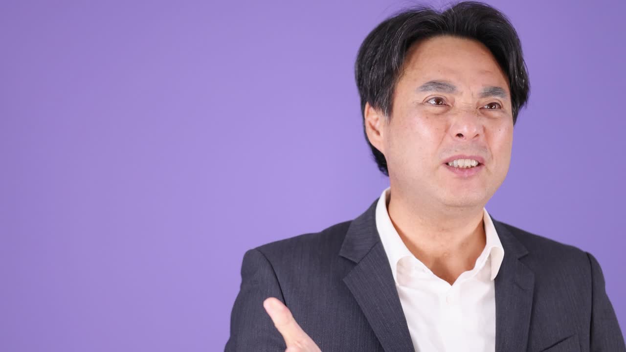 Businessman in suit displays anger and frustration, gesturing passionately against a purple studio background