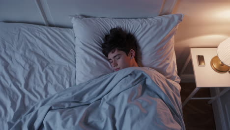 overhead view of a person sleeping peacefully in bed at night