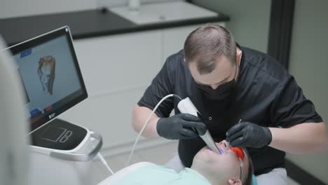 el médico escanea los dientes del paciente en la clínica. el dentista sostiene en su mano un escáner 3d manual para la mandíbula y la boca. salud dental. crea un modelo 3d de dientes y encías en un monitor médico.