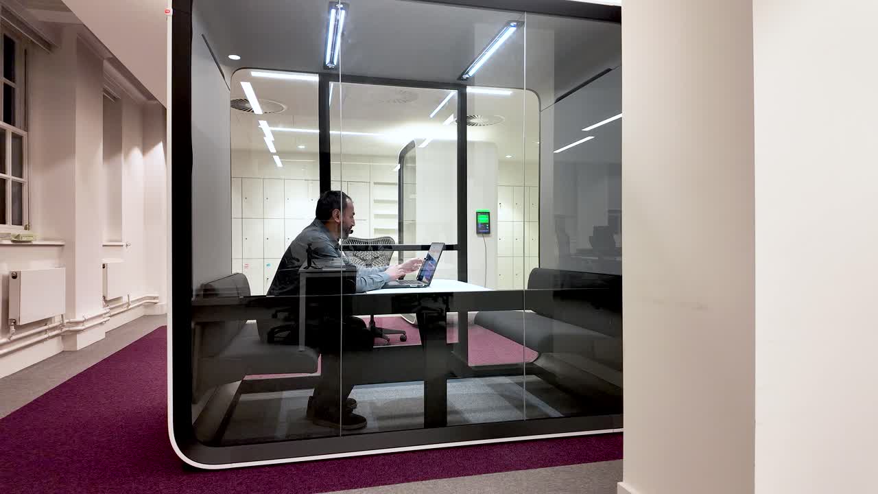 Sørasiatisk kontorarbeider går inn i moderne møteboks i glass med laptop og stoler. Forretningsteknologi og konsept for samarbeid på arbeidsplassen