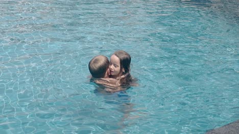 happy children hug and swim in pool water slow motion