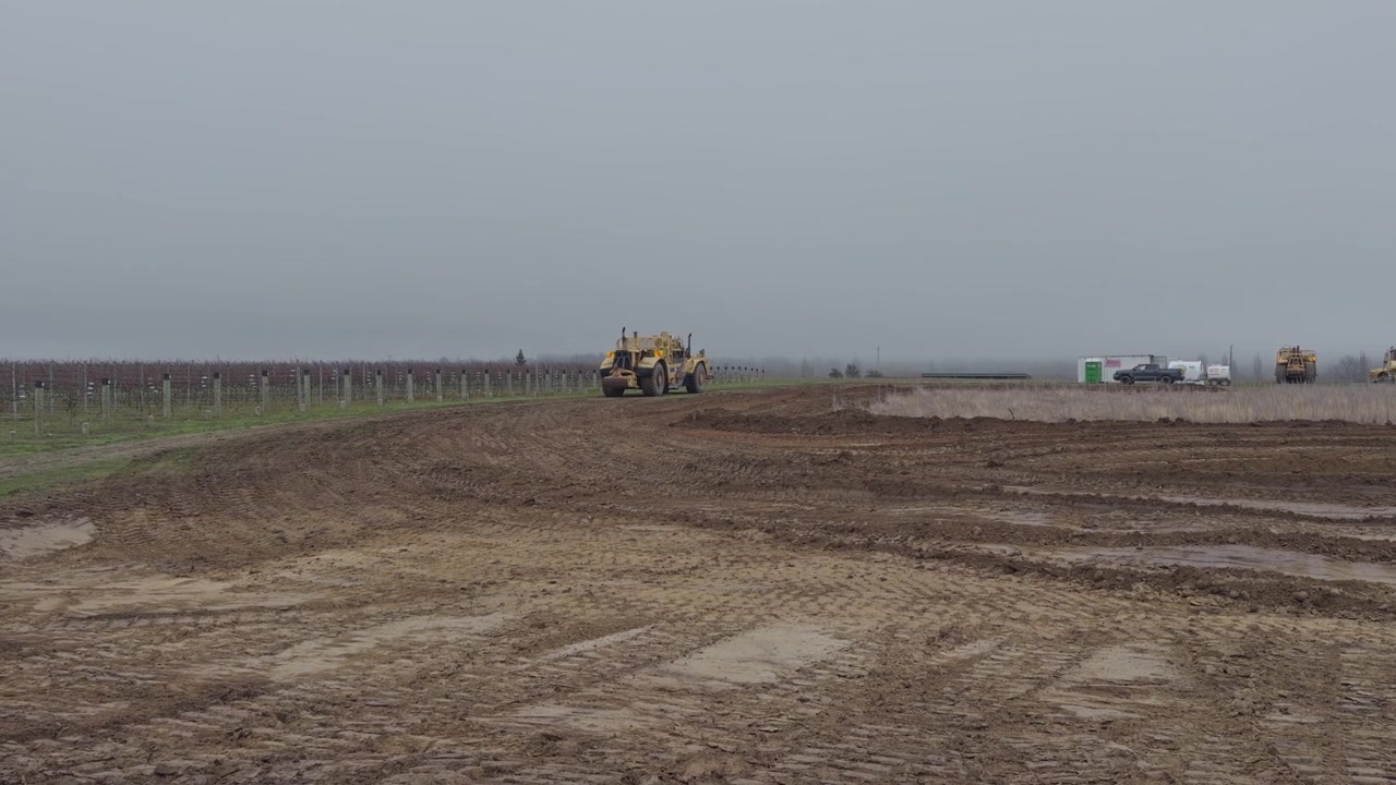 Uno scraper gommato rimodella e livella il terreno per lo sviluppo di terreni agricoli nell'Otago Centrale, Nuova Zelanda. Attrezzature pesanti che operano in un cantiere aperto