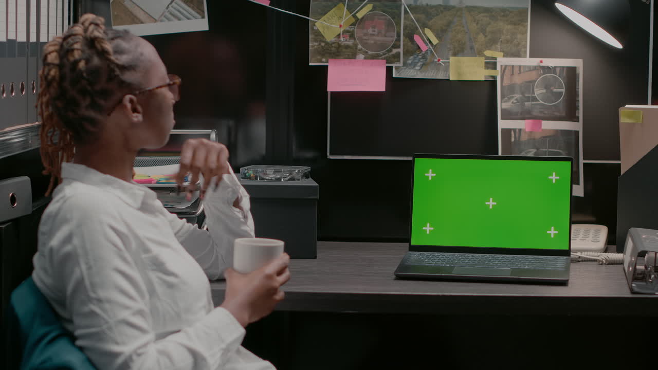 Woman working on laptop with green screen in office