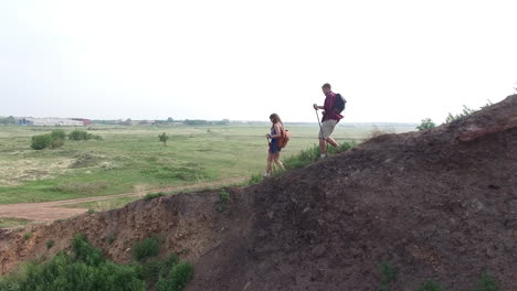 couple hiking down a mountain with views of a vast meadow