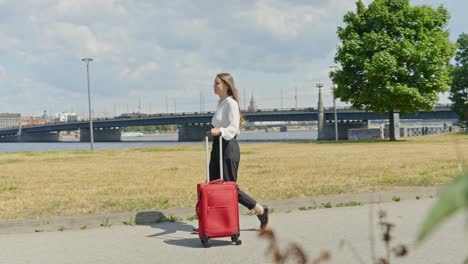 young entrepreneur female travel to new city with red luggage, follow view